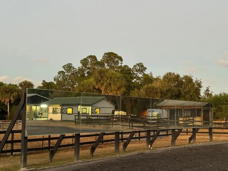The barns lit at dusk behind a black board fence